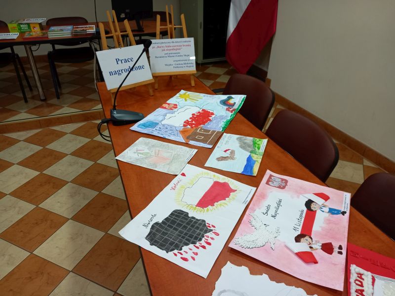 Zdjęcie przedstawia prace konkursowe wyłożone na stole w sali konferencyjnej