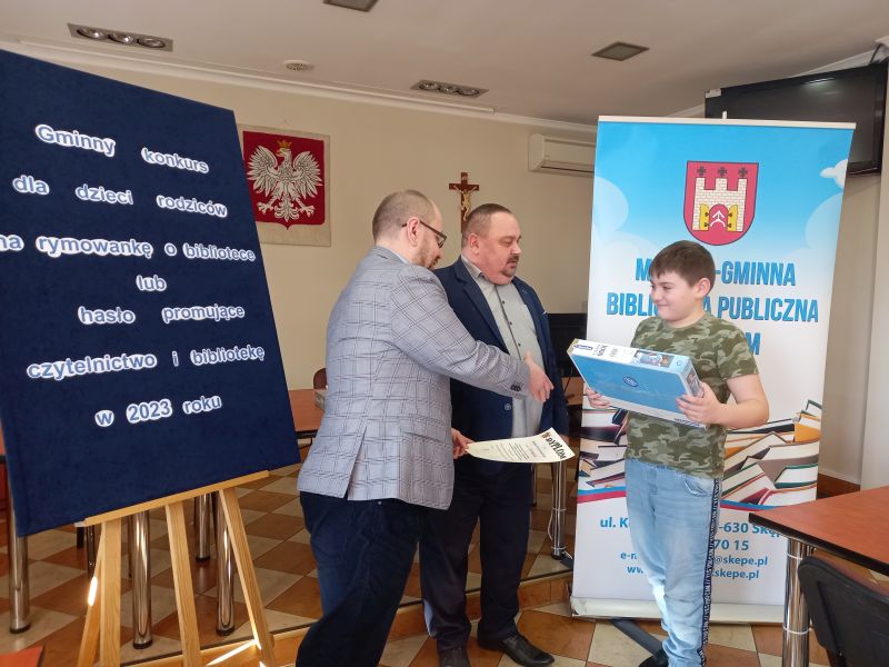 Na zdjęciu przedstawiony jest moment gdy Zastępca Burmistrza Skępego wraz dyrektorem biblioteki wręczają nagrodę laureatowi konkursu