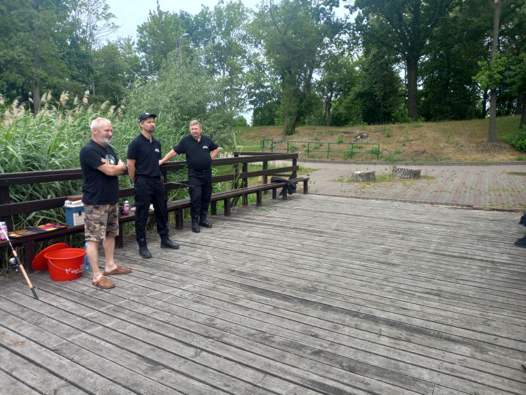 Zdjęcie przedstawia przedstawicieli Stowarzyszenia Ekologiczno- Wędkarskiego „Okoń” stojących na pomości nad jeziorem