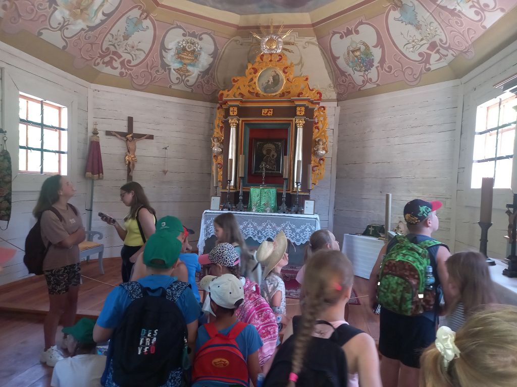 Zdjęcie przedstawia dzieci stojące wewnątrz kościoła w Skansenie