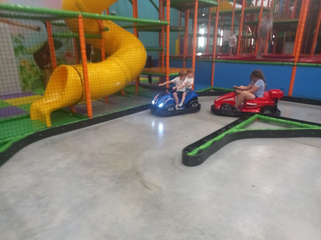 Zdjęcie przedstawia dzieci jeżdżące na Quadach w parku rozrywki