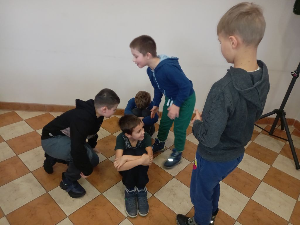 Zdjęcie przedstawia grupę chłopców w trakcie zajęć teatralnych w trakcie ćwiczeń