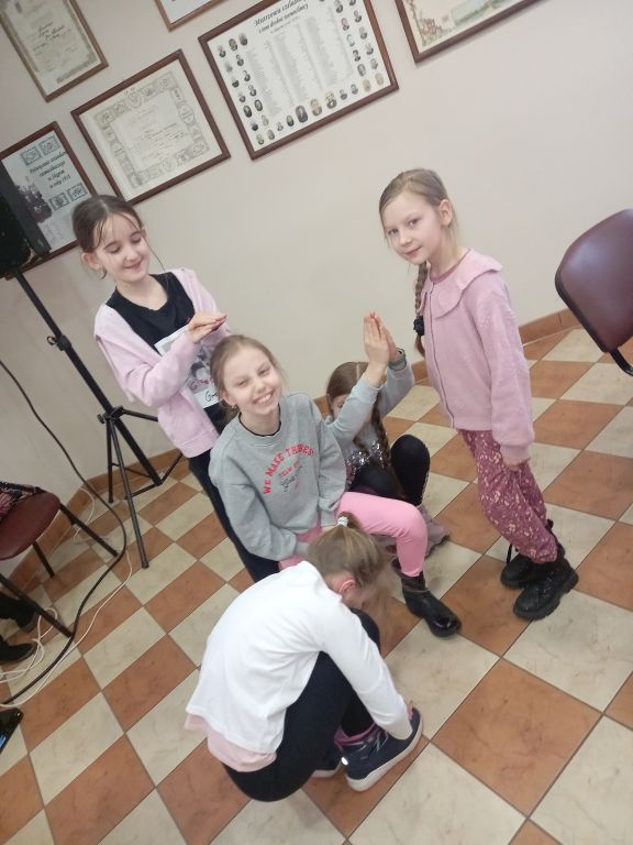Zdjęcie przedstawia grupę dziewczynek w trakcie zajęć teatralnych
