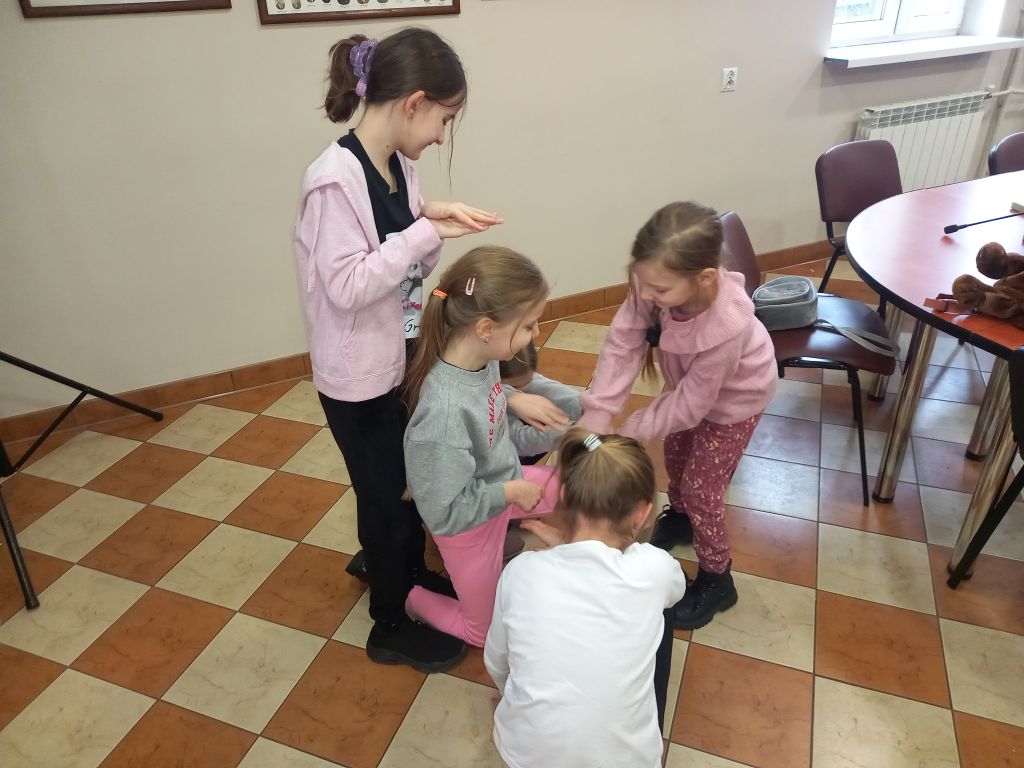 Zdjęcie przedstawia grupę dziewczynek w trakcie zajęć teatralnych