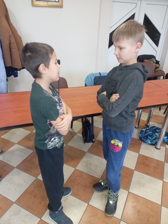 Zdjęcie przedstawia dwóch chłopców stojących w Sali konferencyjnej w trakcie zajęć teatralnych