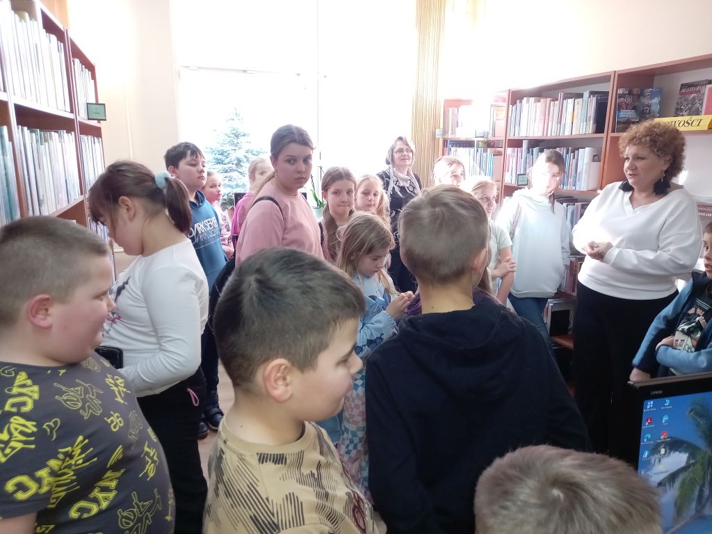 Zdjęcie przedstawia grupkę dzieci i pracowników Biblioteki w Rypinie w trakcie zajęć w bibliotece