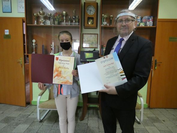 Zdjęcie przedstawia moment wręczenia dyplomu i nagrody zdobytej w konkursie poetyckim w Skępem   Julii Żulewskiej przez Dyrektora Szkoły Podstawowej w Nadrożu
