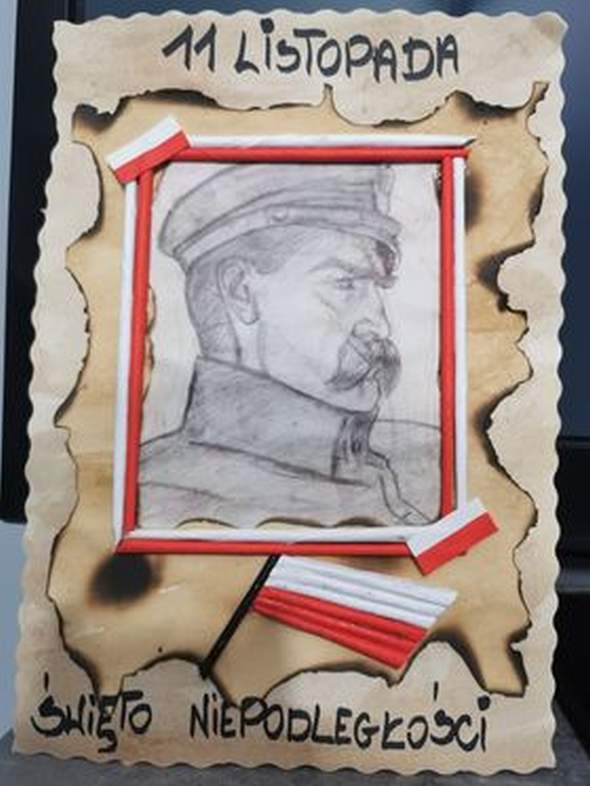 Ilustracja przedstawia pracę Martyny Chojnackiej laureatki III miejsca w kategorii wiekowej powyżej 6 lat. Praca przedstawiam Portret Józefa Piłsudskiego w biało-czerwonej ramce. Nad portretem napis 11 Listopada, pod portretem napis Święto Niepodległości.