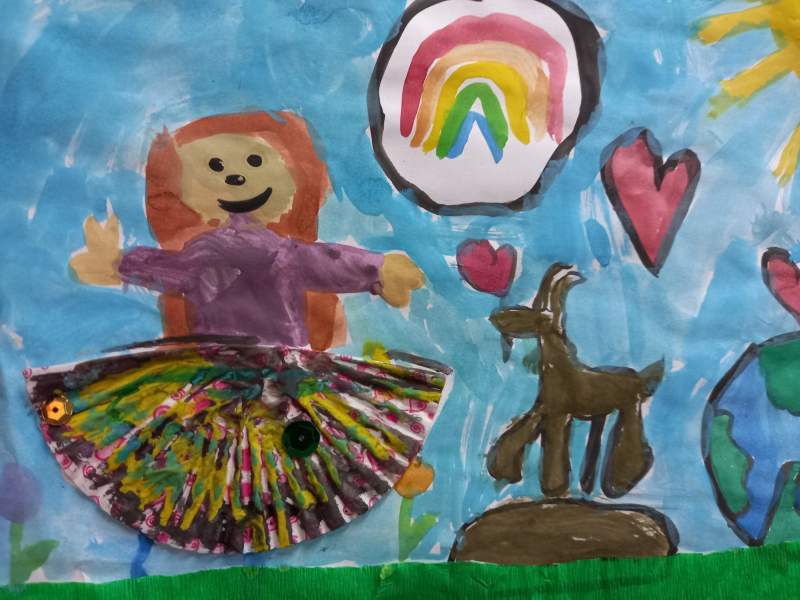 Zdjęcie przedstawia plakat, na którym w pierwszym planie jest postać uśmiechniętej dziewczynki. Na drugim planie widać fontannę ze skępskim koziołkiem, oraz serduszka i namalowaną kulę ziemską