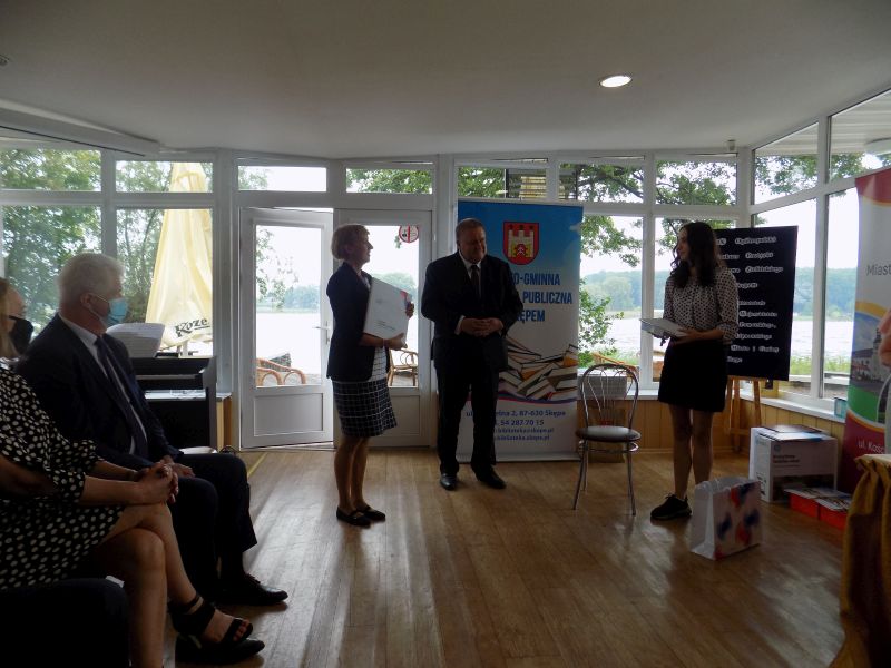 Zdjęcie przedstawia przedstawiciela KPCEN we Włocławku i  Członka Zarządu Województwa Kujawsko Pomorskiego wręczających nagrodę uczestniczce konkursu