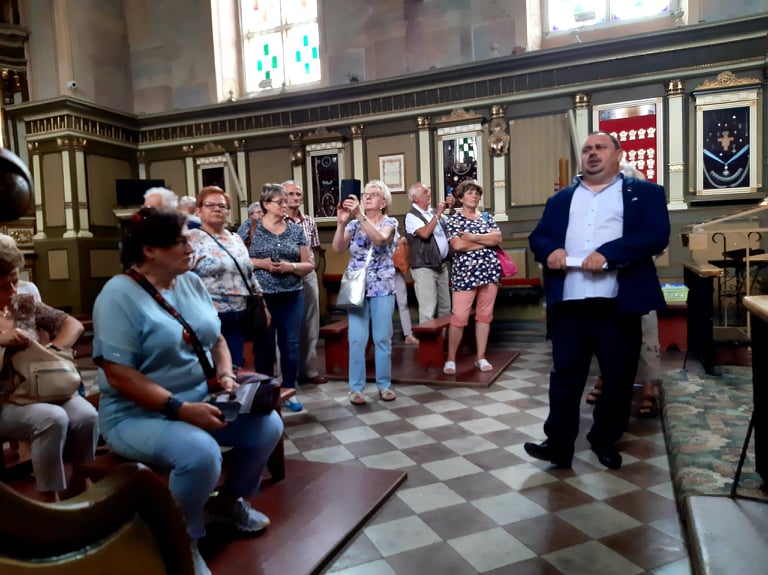 Na zdjęciu widać uczestników wycieczki w kościele słuchających informacji dyrektora biblioteki o historii skępskiego kościoła