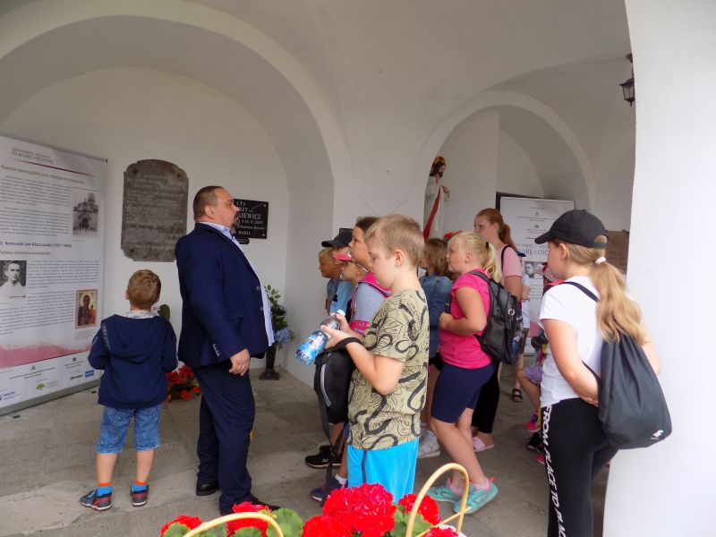 Na zdjęciu widać dyrektora biblioteki wraz z dziećmi stojących na krużgankach w klasztorze w Skępem