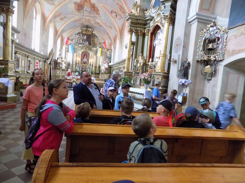 Na zdjęciu widać dyrektora biblioteki wraz z dziećmi stojących w klasztorze w Skępem