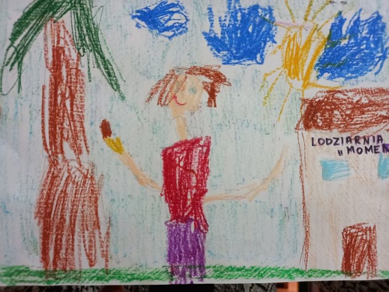 Zdjęcie przedstawia pracę laureata trzeciego miejsce w kategorii do 6 lat Zuzanny Alaszkiewicz. Praca wykonana kredkami przedstawia dziewczynkę bawiącą się w piasku na plaży nad jeziorem