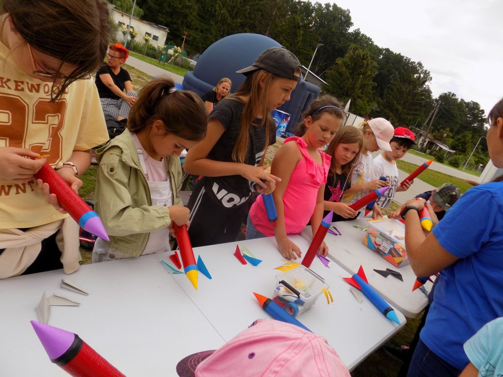 Fotografia przedstawia uczestników zajęć budujących rakiety z papieru. Wszystkie dzieci są bardzo zaangażowane