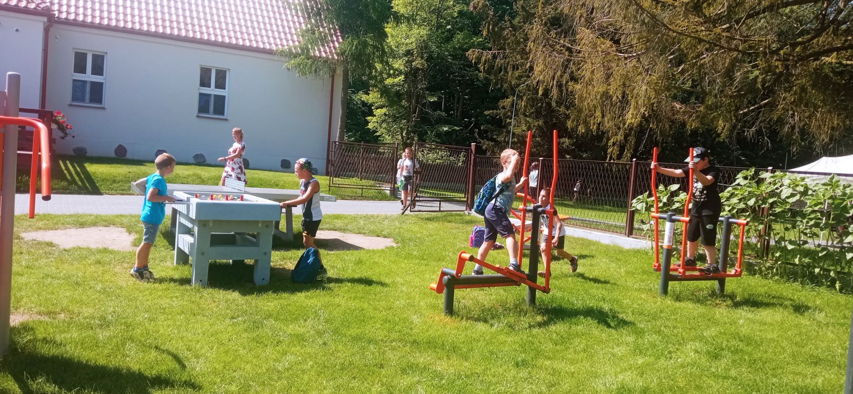 Fotografia przedstawia uczestników zajęć bawiących się na terenie Ośrodka Wypoczynkowego w Górznie. Dzieci korzystają z piłkarzyków, siłowni i stołu do tenisa