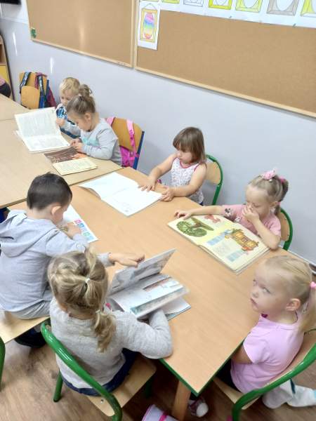 Na zdjęciu widać wnętrze jednej z klas w szkole podstawowej w Wólce, a w niej dzieci siedzące przy stolikach czytające książki i wiersze