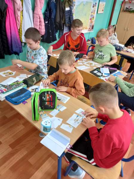 Na zdjęciu widać chłopców układających puzzle związane z dniem głośnego czytania. Siedzą trójkami przy stolikach