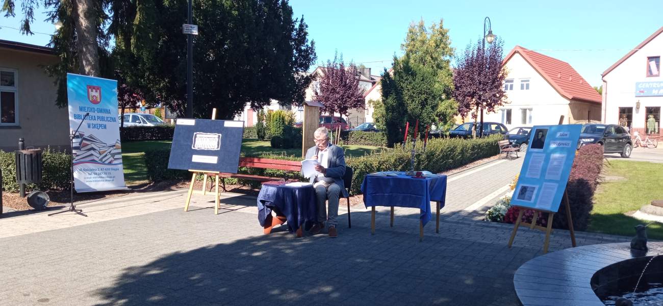 Zdjęcie przedstawia przewodniczącego Rady Miejskiej Janusza Kozłowskiego siedzącego przy stoliku i czytającego kolejny wiersz Adama Mickiewicza
