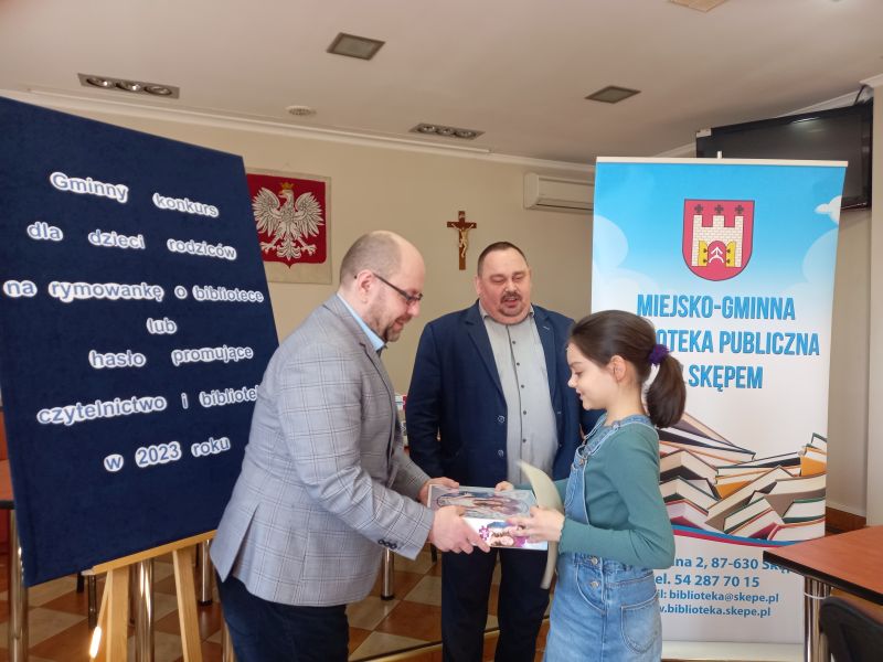 Na zdjęciu przedstawiony jest moment gdy Zastępca Burmistrza Skępego wraz dyrektorem biblioteki wręczają nagrodę laureatce konkursu