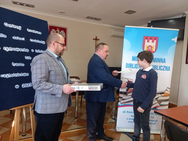 Na zdjęciu przedstawiony jest moment gdy Zastępca Burmistrza Skępego wraz dyrektorem biblioteki wręczają nagrodę laureatowi konkursu