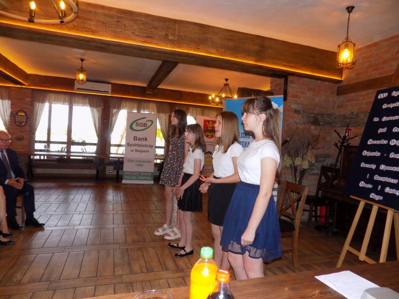 Fotografia przedstawia stojące dziewczyny i śpiewającą piosenkę w Sali w której odbywa się gala konkursowa