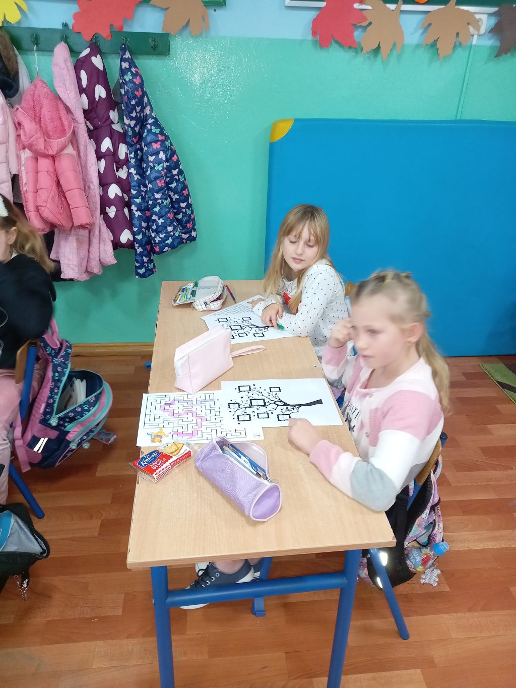 Zdjęcie przedstawia dziewczynki siedzące w trakcie lekcji w klasie w ławce