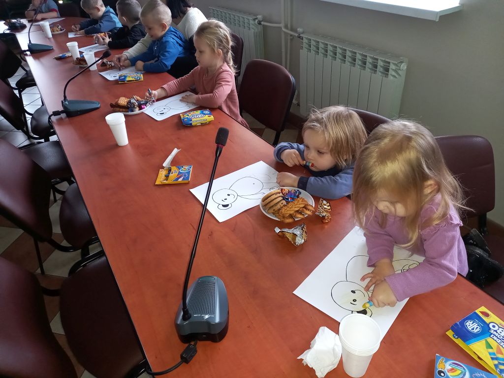 Zdjęcie przedstawia przedszkolaków siedzących przy stołach w trakcie prac plastycznych