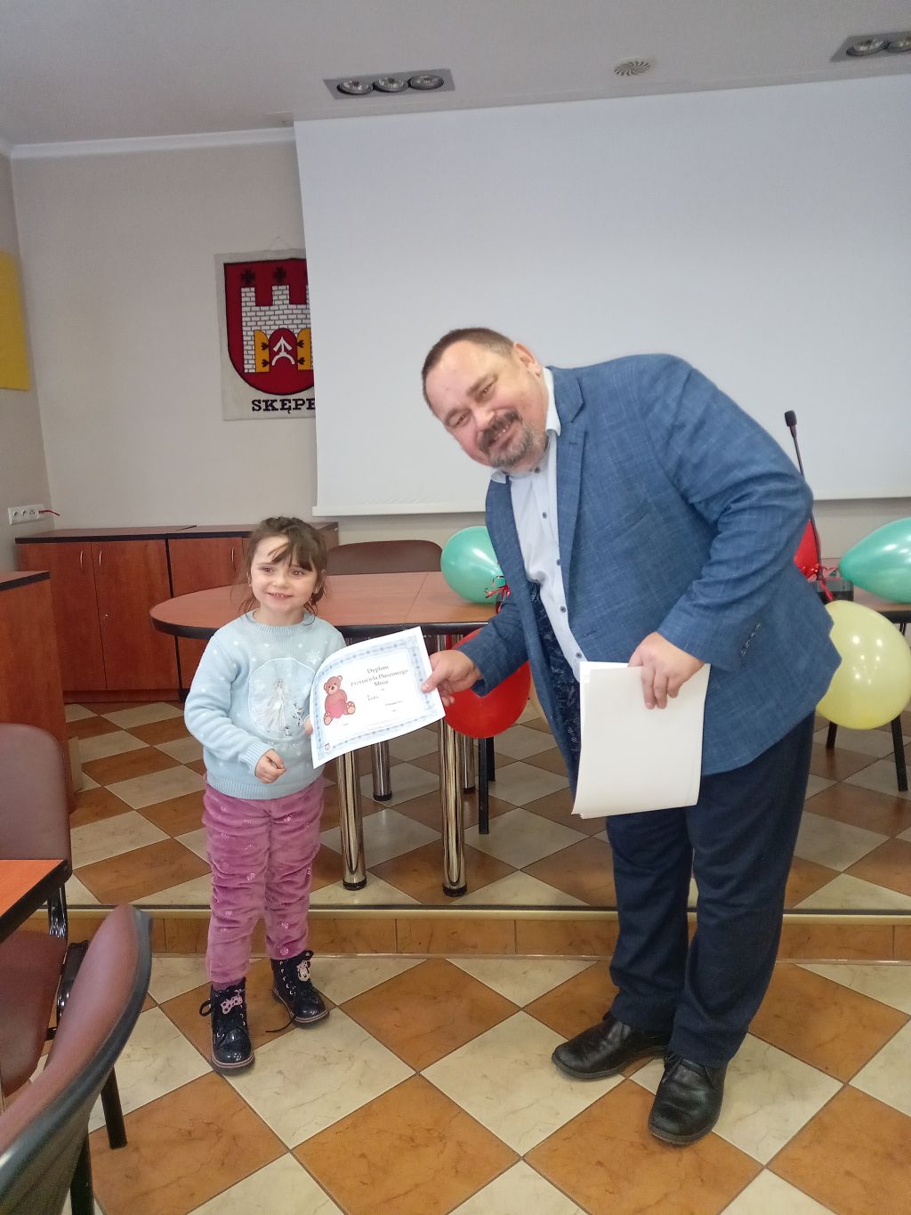 Zdjęcie przedstawia dyrektora biblioteki wręczającego dziecku dyplom Przyjaciela Pluszowego Misia