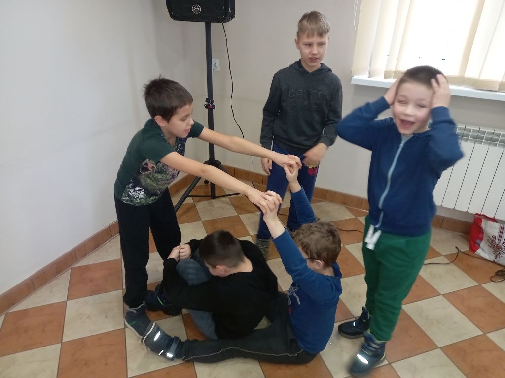 Zdjęcie przedstawia grupę chłopców w trakcie zajęć teatralnych w trakcie ćwiczeń