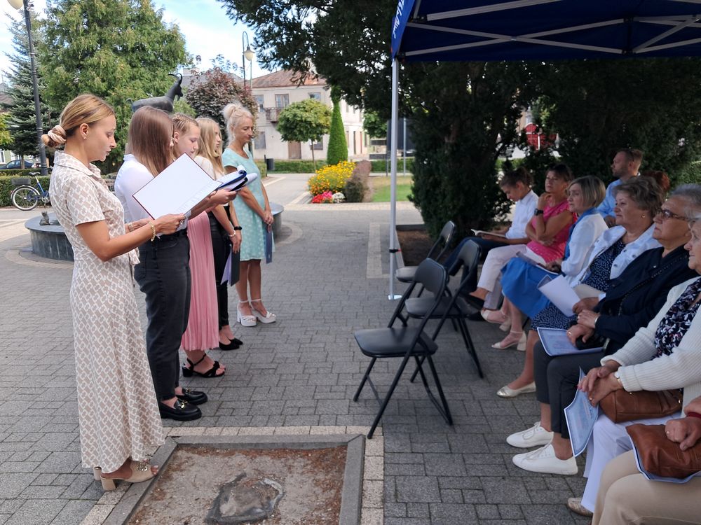 Zdjęcie przedstawia uczniów i nauczycieli Szkoły Podstawowej w Wólce stojących przed uczestnikami spotkania i czytających lekturę Kordiana